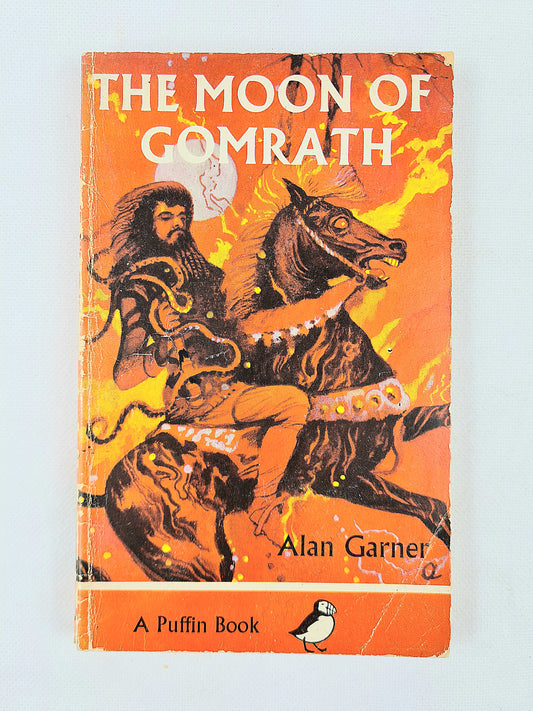 Book cover of 'The Moon of Gomrath' by Alan Garner with an illustration of a man on a horse.