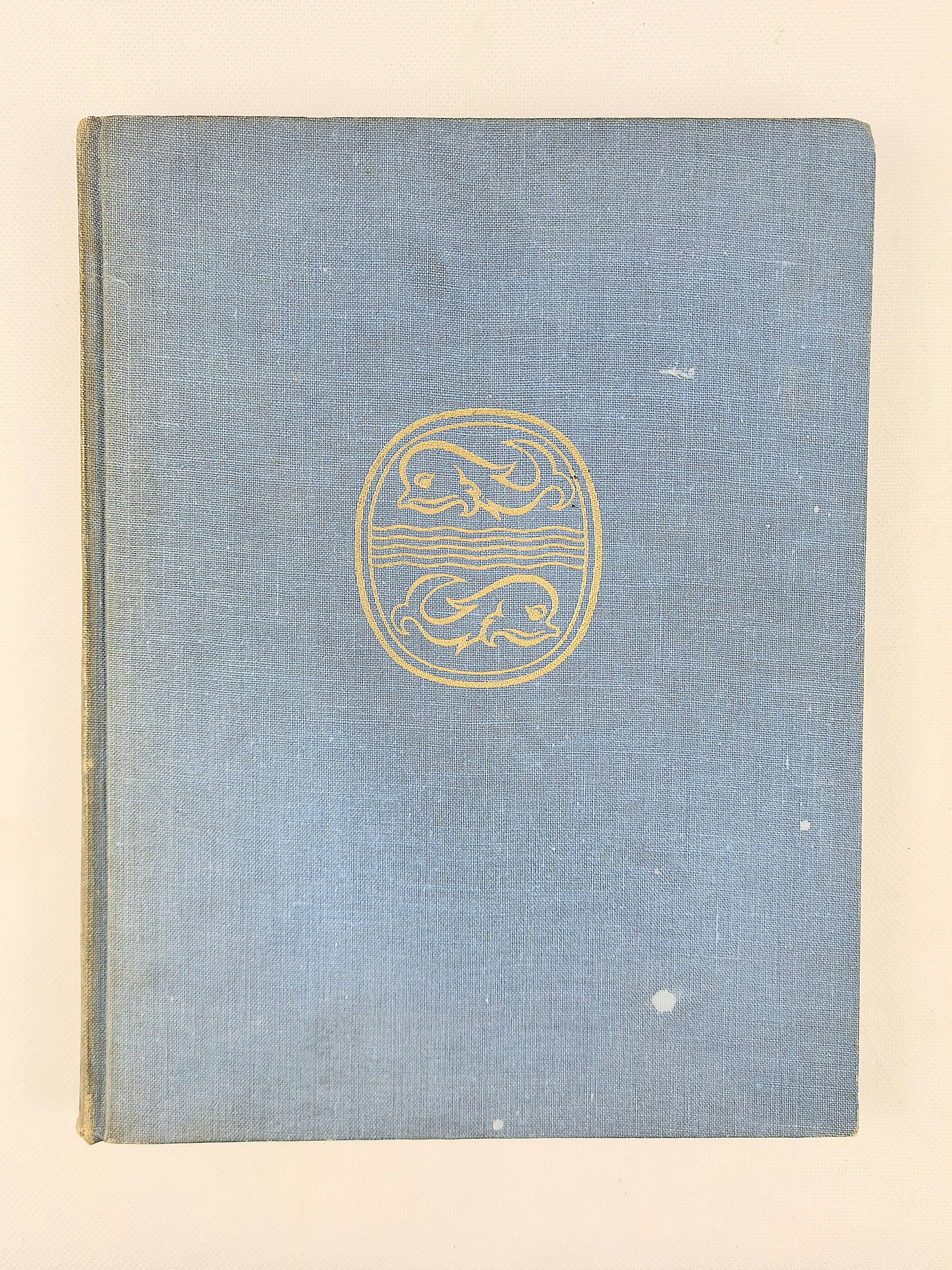 Blue book cover with a gold emblem on a beige background