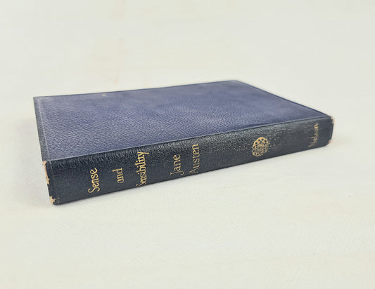 A vintage hardcover book with a textured navy blue leather cover and gold lettering on the spine, photographed on a light off-white background.