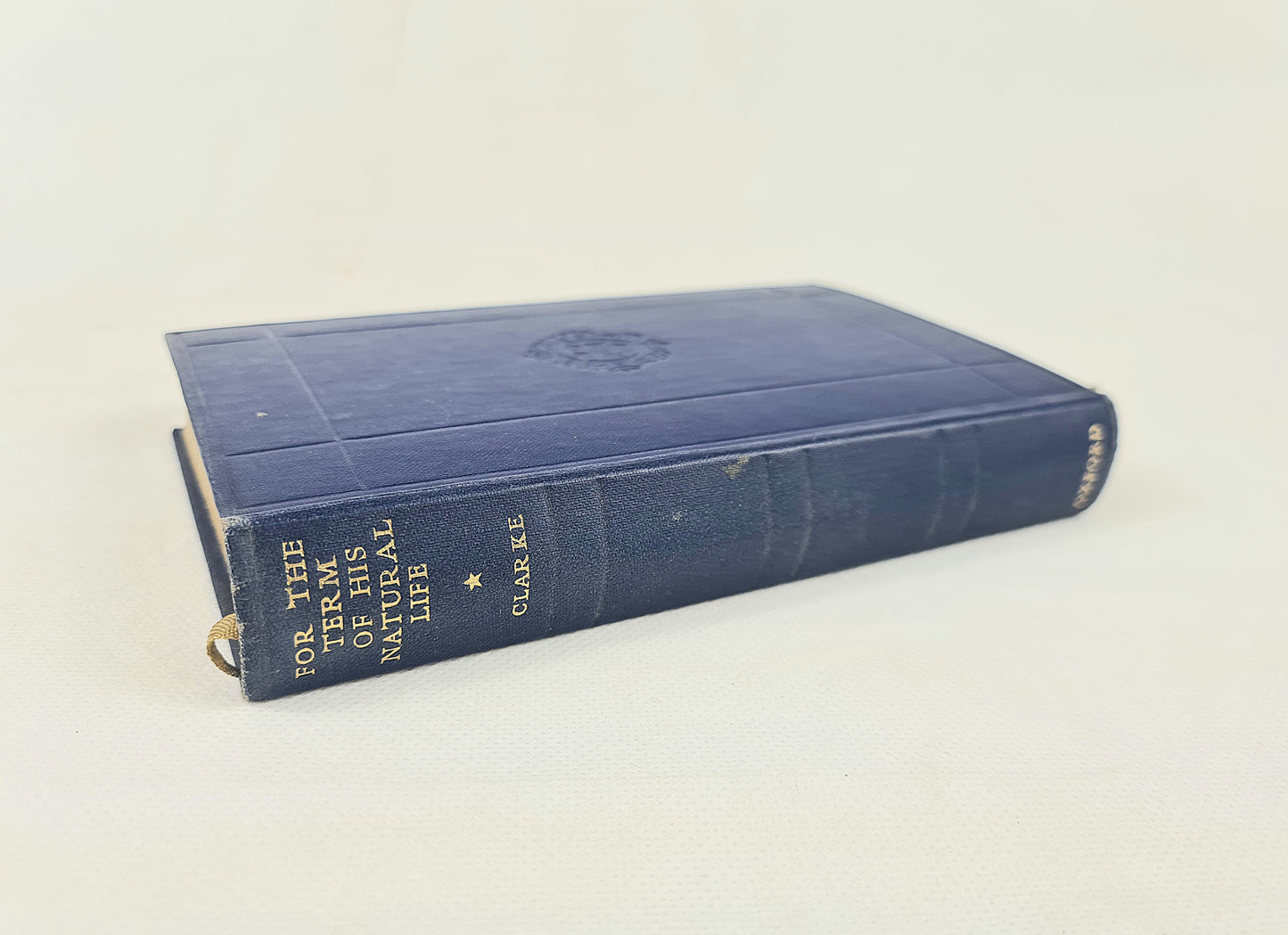 A vintage hardcover book titled 'For the Term of His Natural Life' by Marcus Clarke, featuring a dark blue cloth-bound cover with gold lettering on the spine, photographed on a light off-white background.
