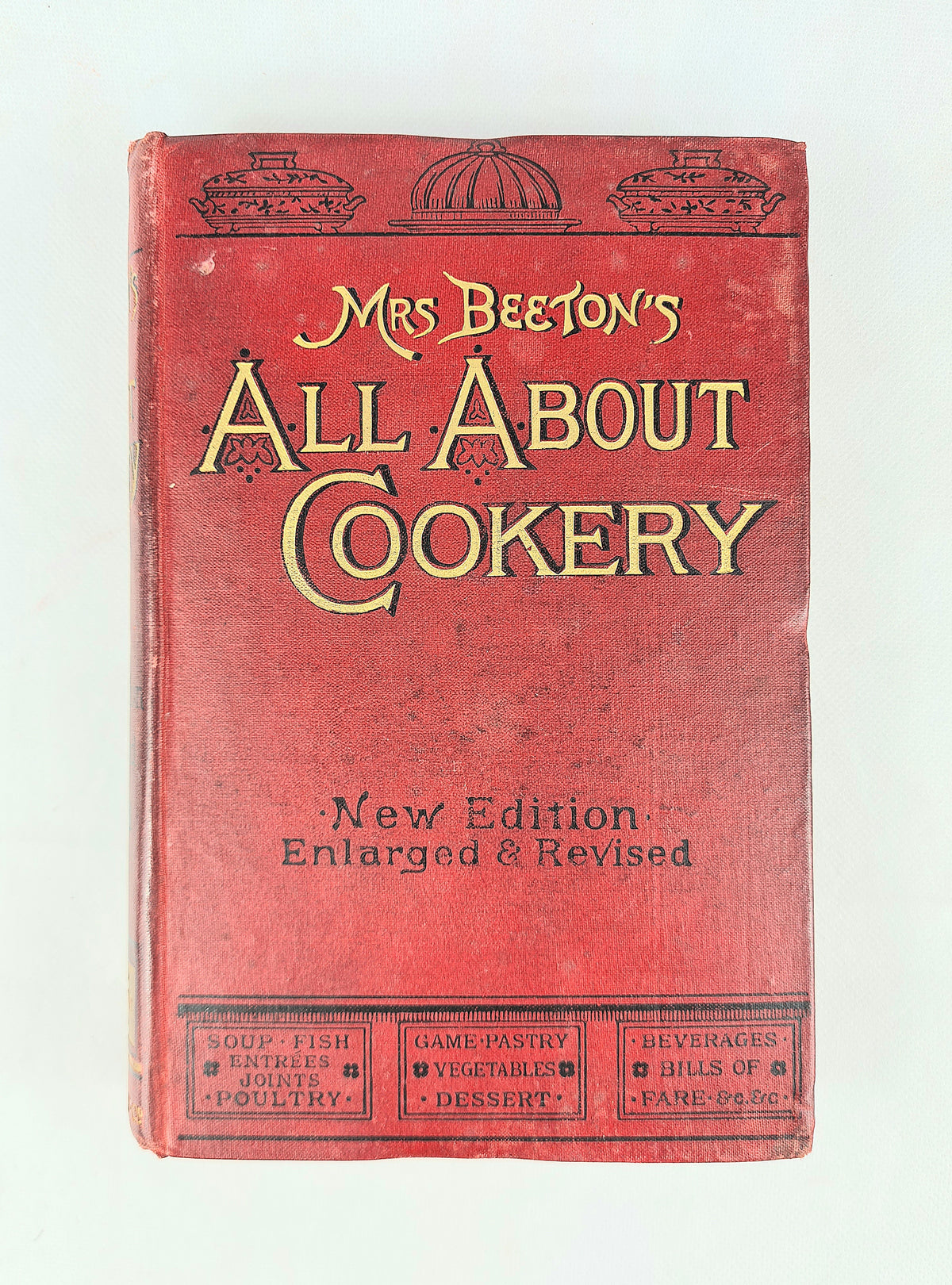 Vintage hardcover book titled 'Mrs Beeton's All About Cookery' in red with gold lettering, photographed against a plain light background.